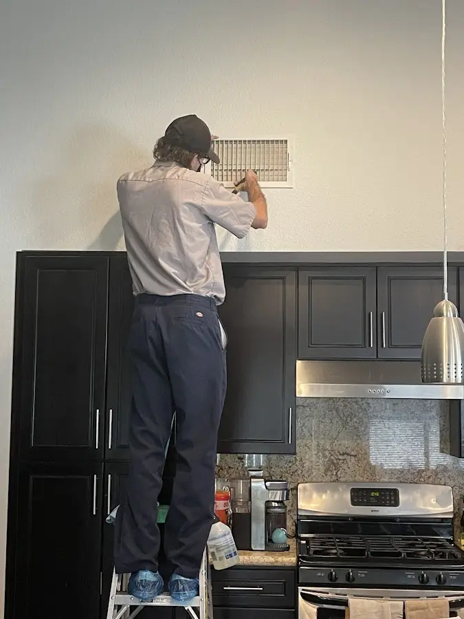 Technician inspecting an air vent during HVAC service in Appleton